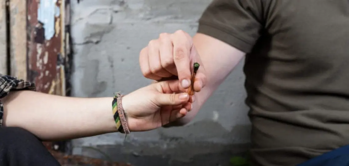 close up of a teen girl passing a joint to a teen boy