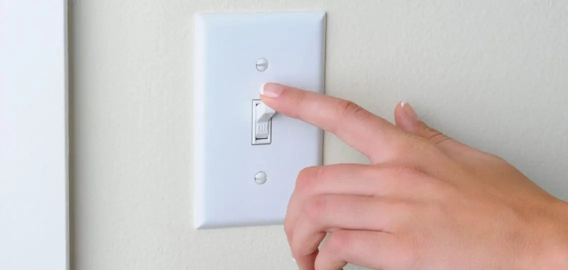 hand turning off a light switch