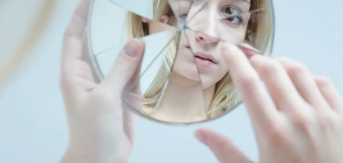 girl with bad body image looking in a shattered mirror
