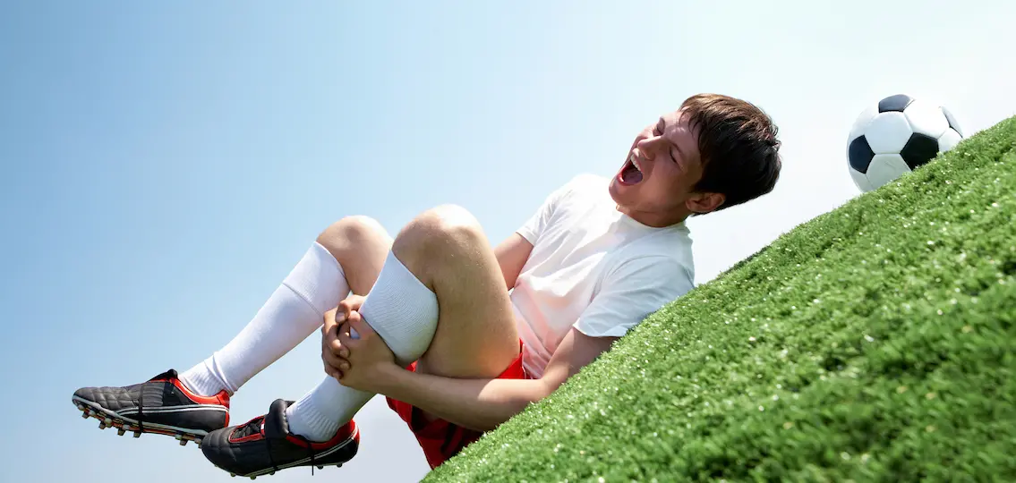 Image of teen soccer player lying down and shouting in pain