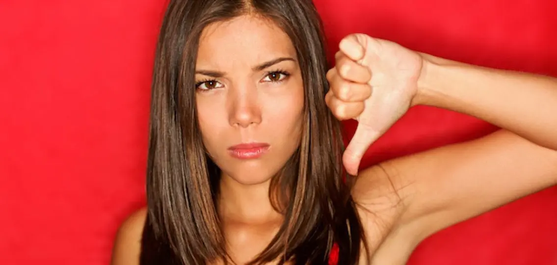 angry teen girl on red background giving a thumbs down