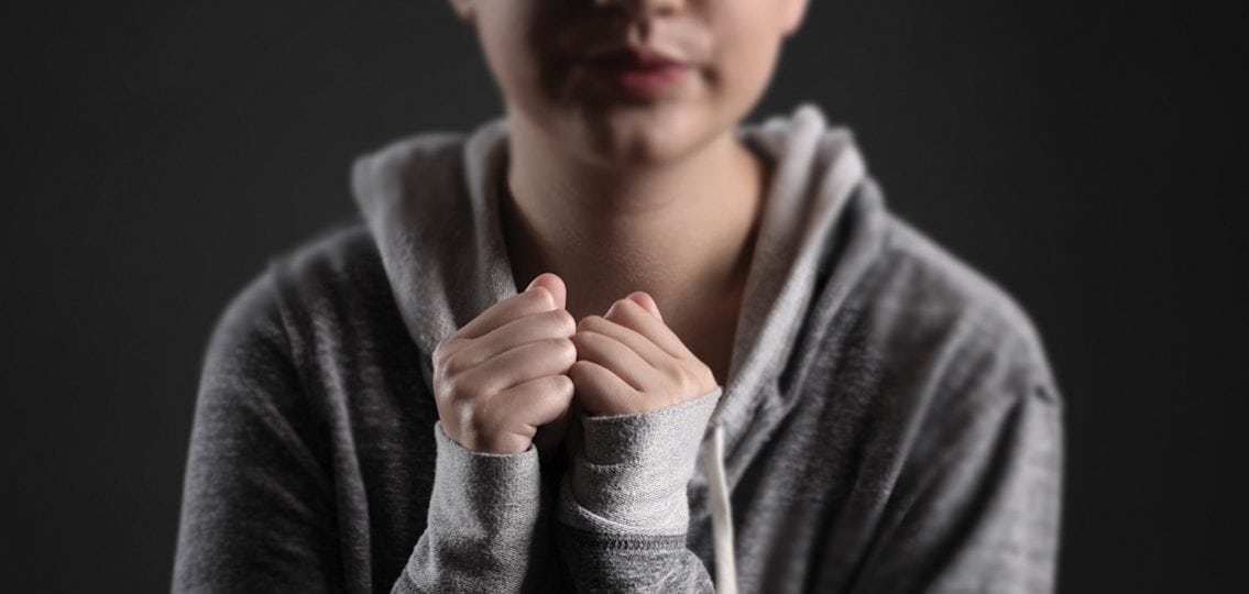 close up of a teen in a hoodie covering her wrists
