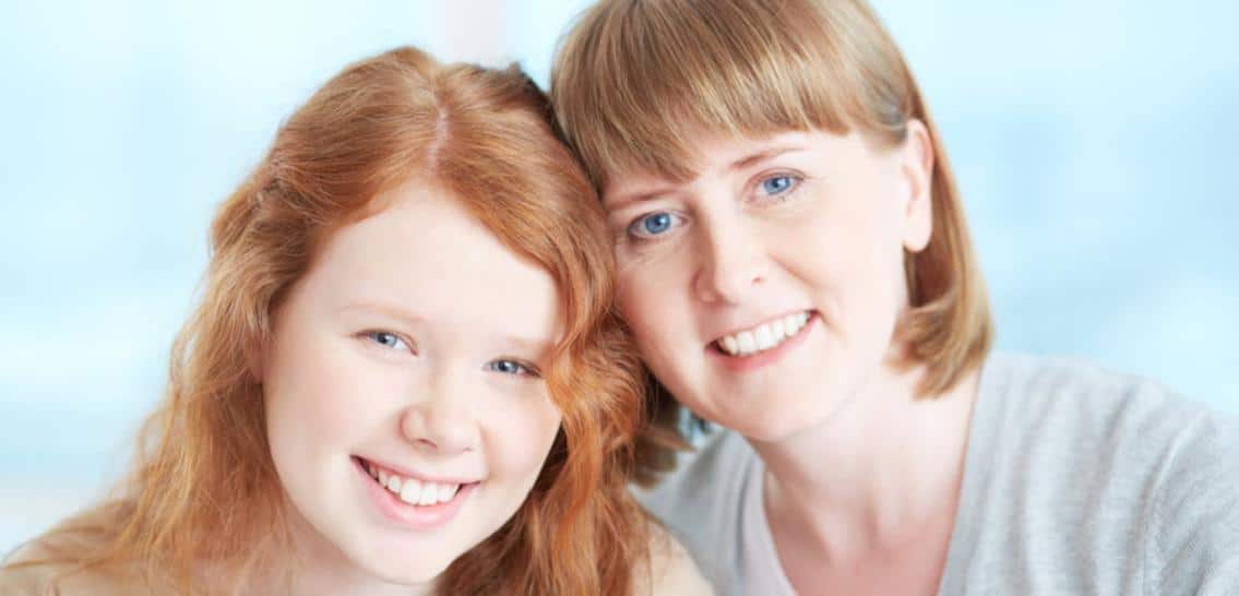 smiling cheerful mom and daughter on blue background