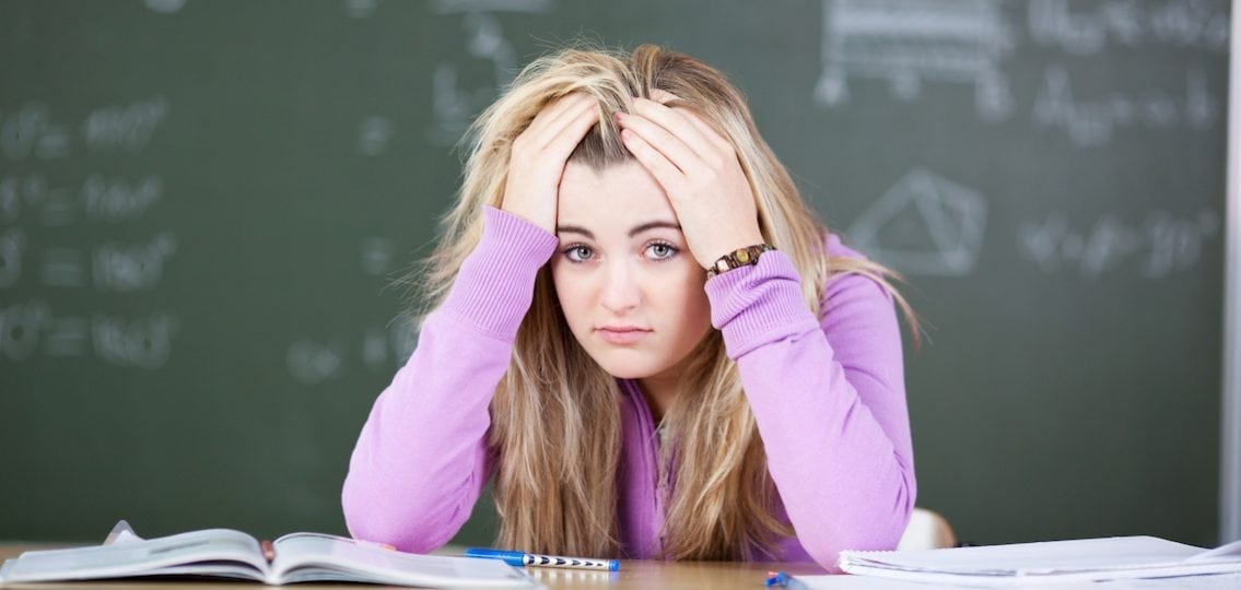 teen stressed working on homework in front of a blackboard