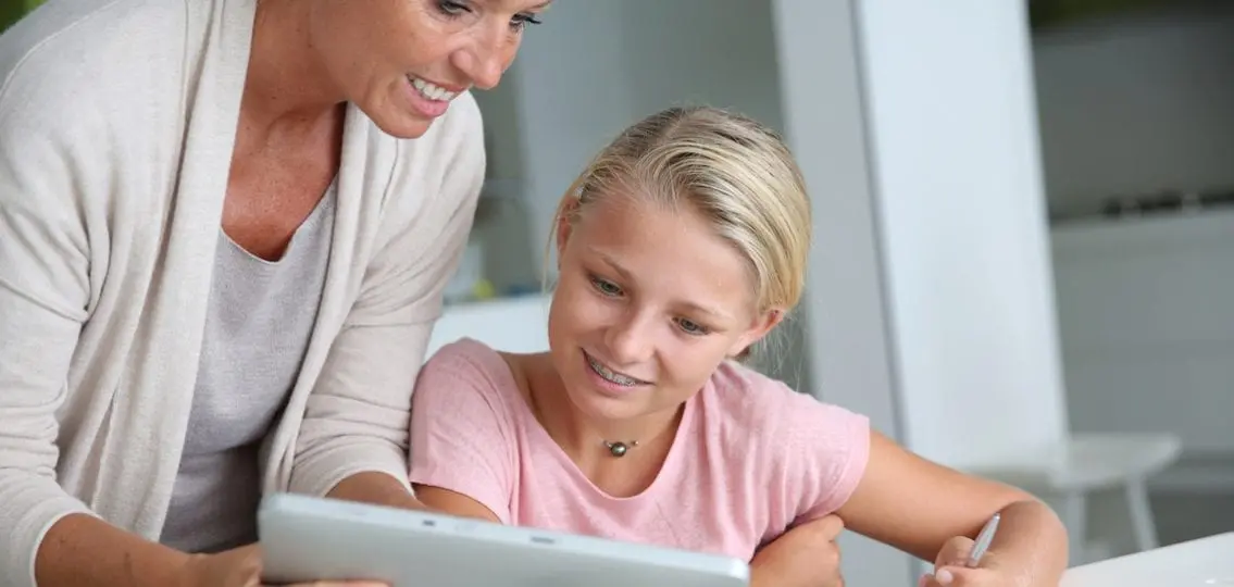 Mother Helping Girl With Homework on a computer