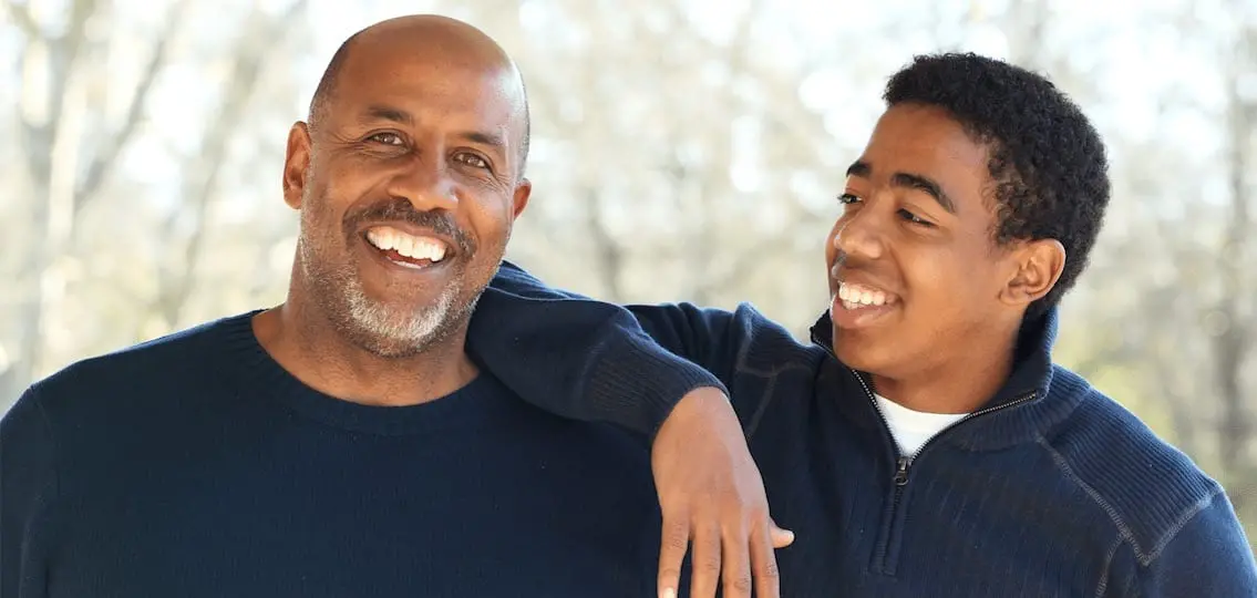 Father smiling while Son puts his arm on dad's shoulder