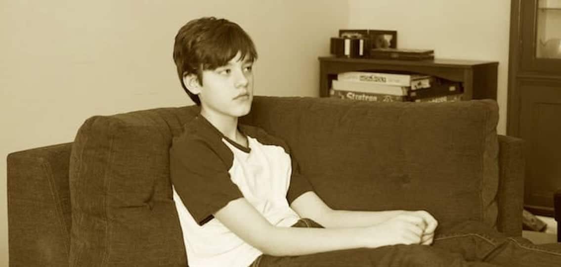 depressed teenage boy on couch sepia tone