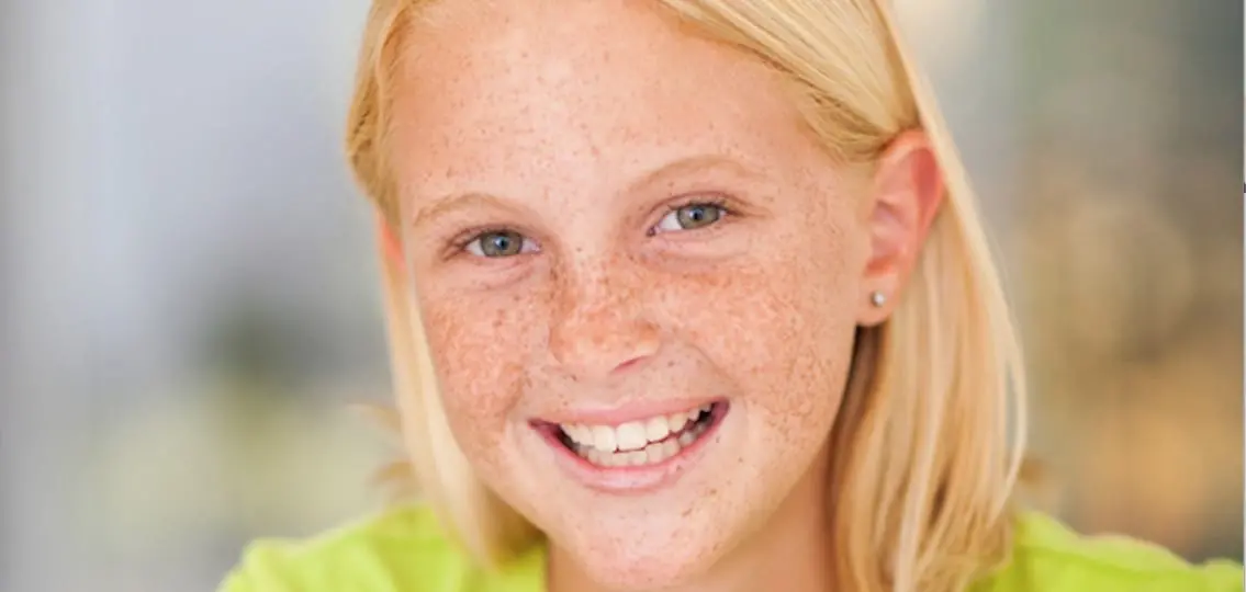 Smiling freckled teen girl close up