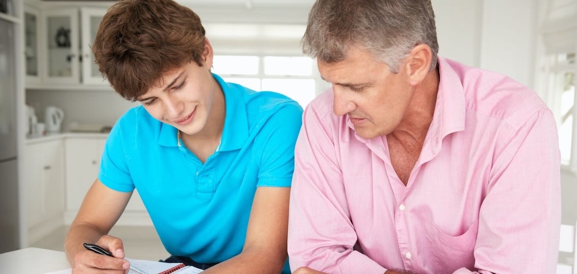 dad and son doing homework together in a white kitchen