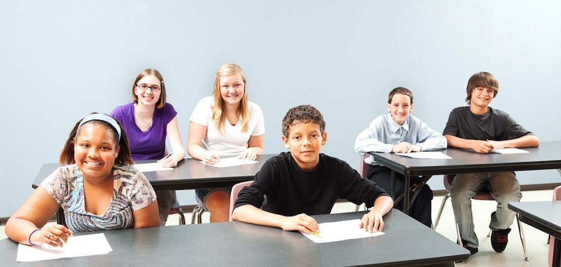 middle school classroom kids sitting at desks and smiling