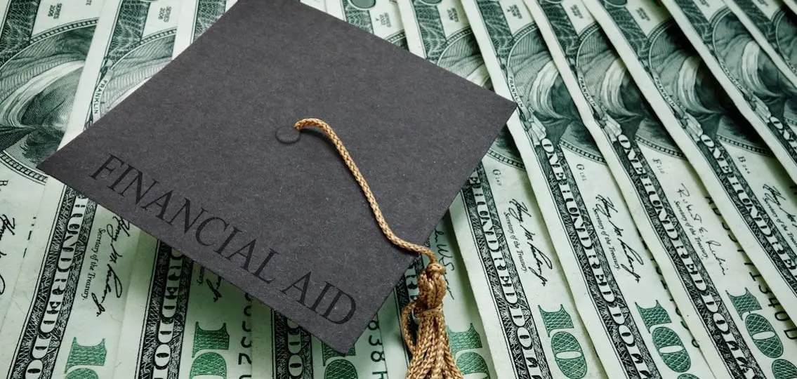 money and graduation hat labeled financial aid