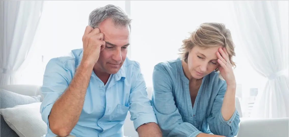 stressed couple thinking and rubbing their heads