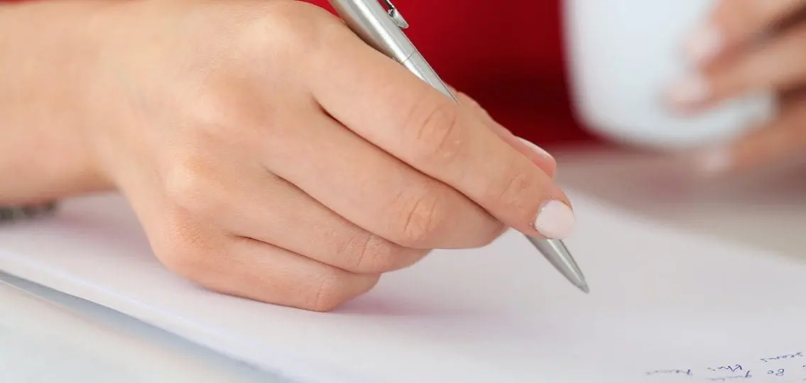hand with pen writing an essay