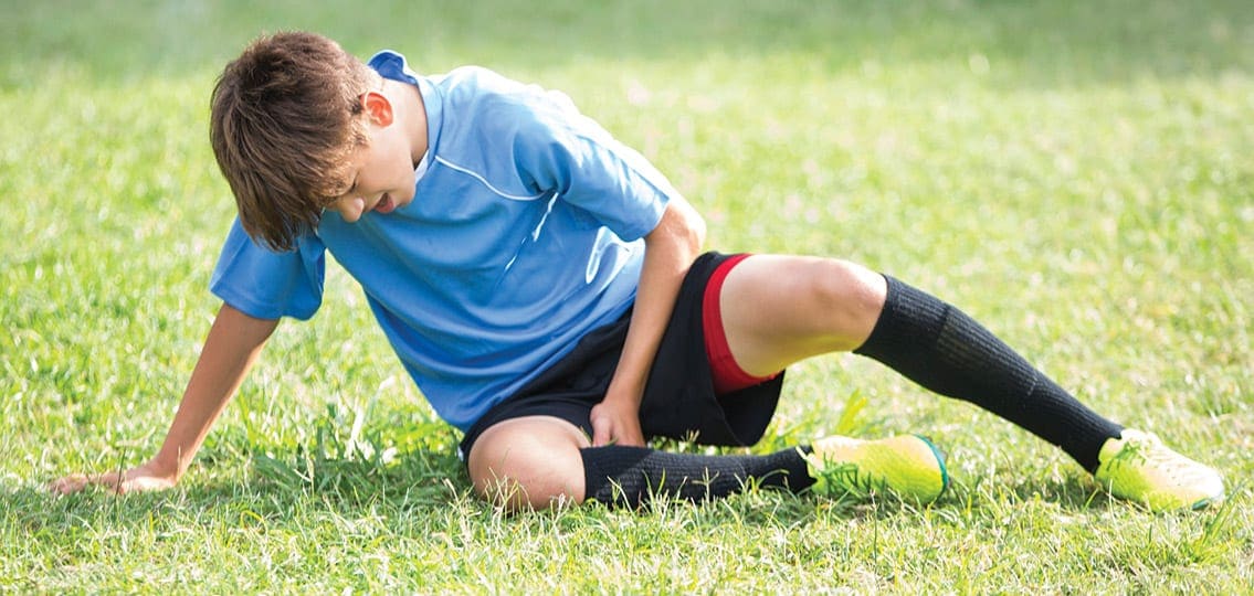 teenage soccer player athlete lying injured on the soccer field