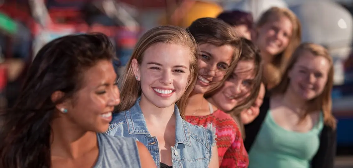 Smiling teenage girls standing behind each other in line