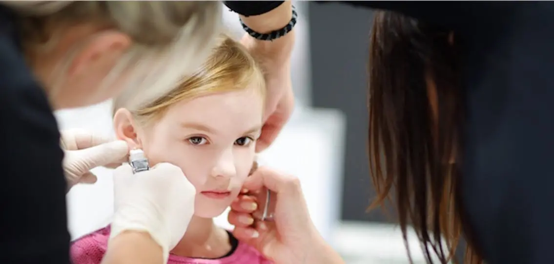 young girl getting ear pierced professionally