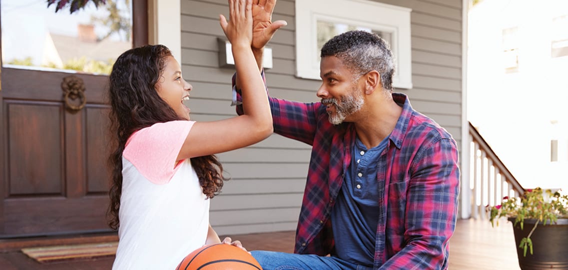Father And Daughter Discussing Basketball On Porch Of Home high fiving