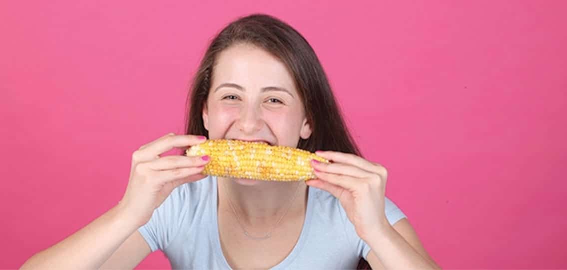 teen Girl Eating Corn on a pink background