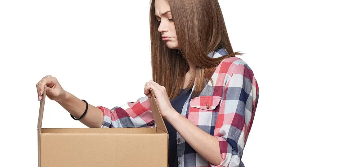 Side view a discontent disappointed girl opening a box