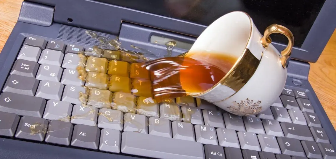 Spilling tea On a Keyboard close up ruining computer