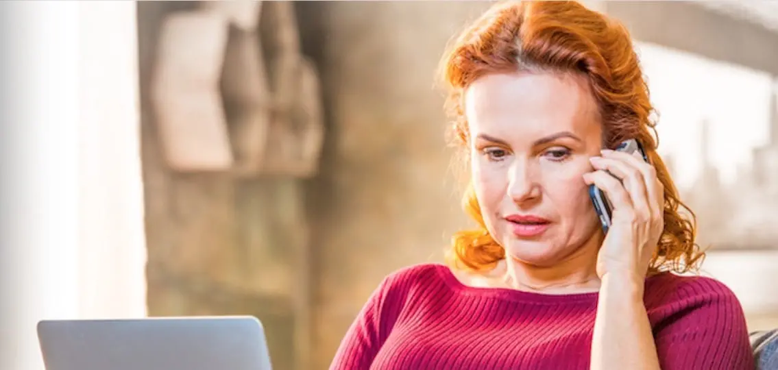 Worried woman on phone in front of laptop