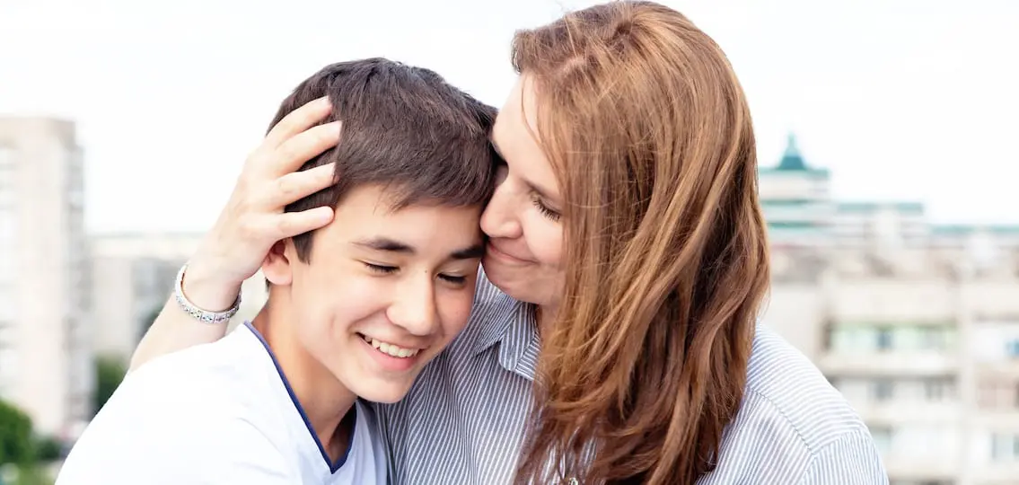mom and teenage son hugging and smiling