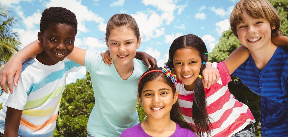 Portrait Of Happy middle schoolers Forming Huddle At The Park