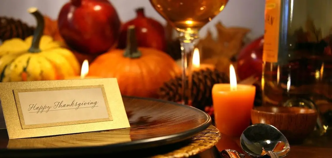 Place setting ready for Thanksgiving surrounded by fall gourds candles and wine