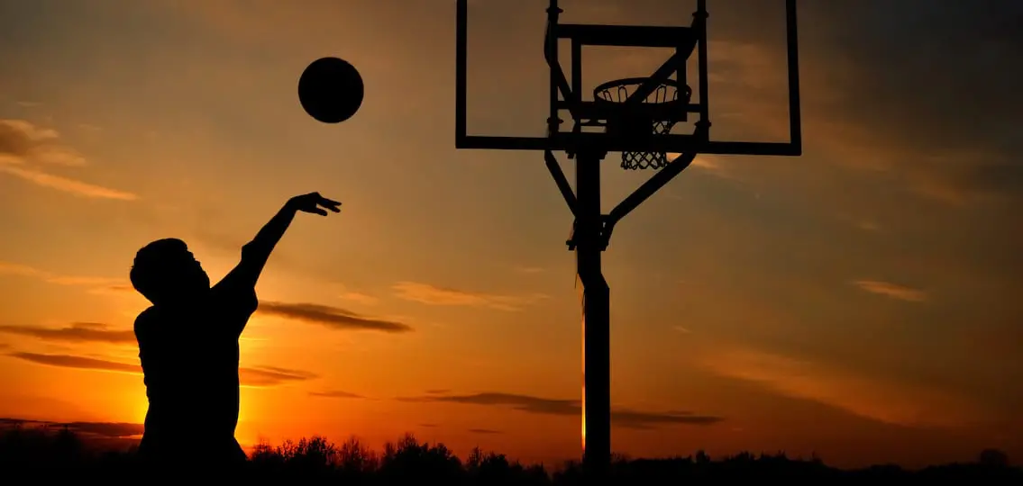 Silhouette of Teen Boy Shooting a Basketball at Sunset