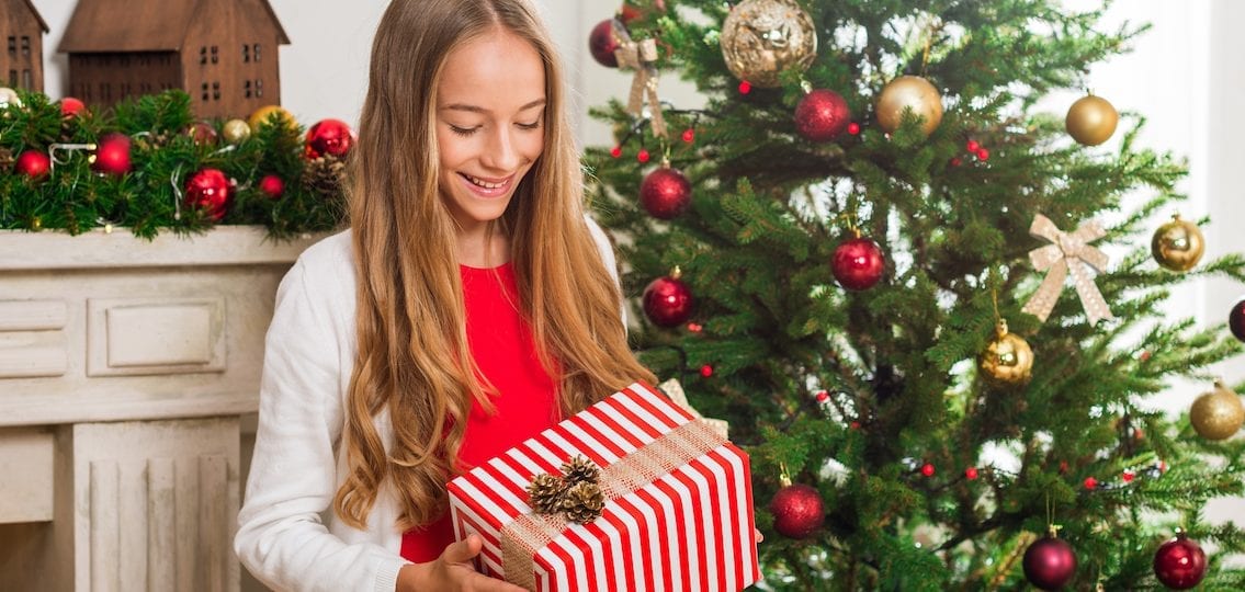 Girl opening a present in front of a christmas tree