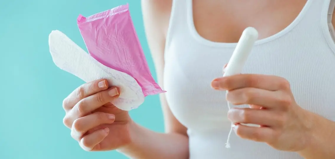 girl holding a pad in one hand and a tampon in the other comparing
