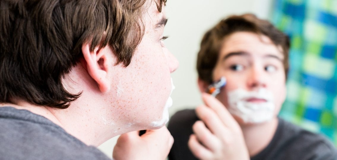 Boy shaving his face for the first time