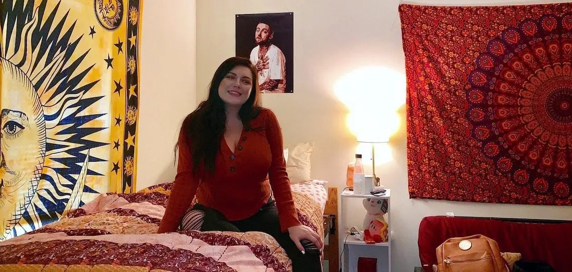 college student in her dorm room decorated with wall hangings