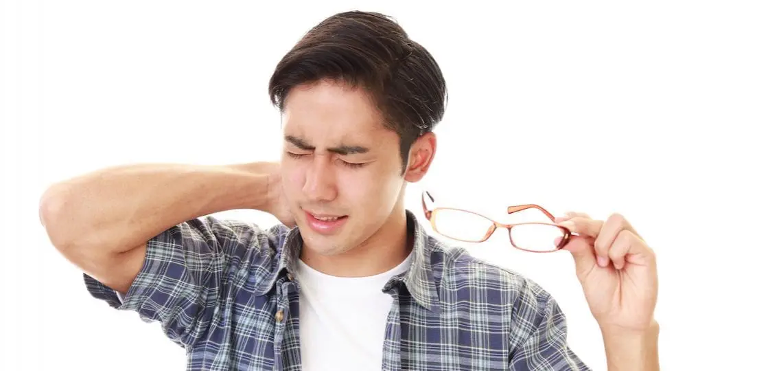 college student boy rubbing his neck in pain taking off glasses