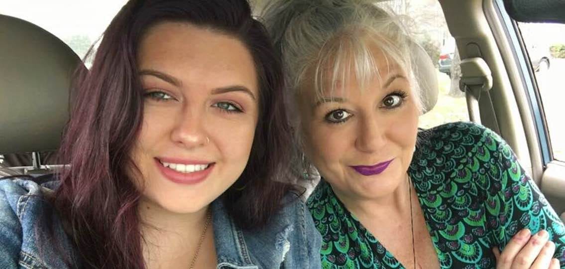 mother and her teen daughter smiling knowingly in the camera in a car