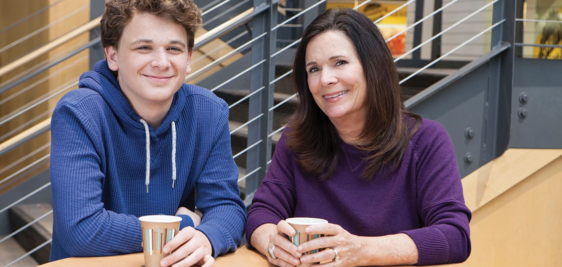teen boy and mom drinking coffee by stairs