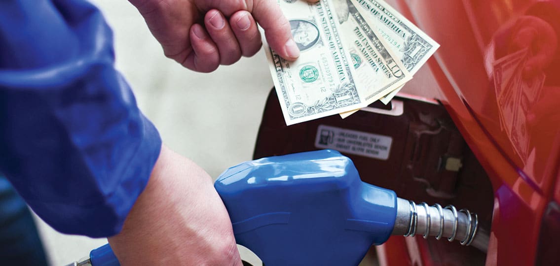 teenager Filling up gas holding twelve dollars