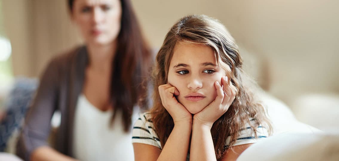Teen girl ignoring her mom looking sad while mom is blurred in the background
