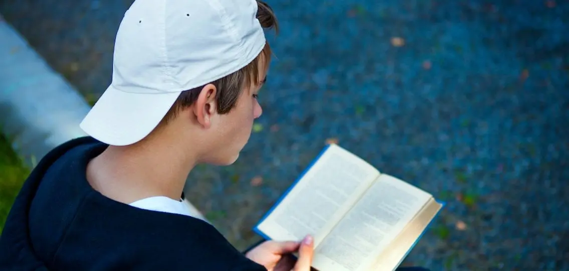 Boy reading books outside