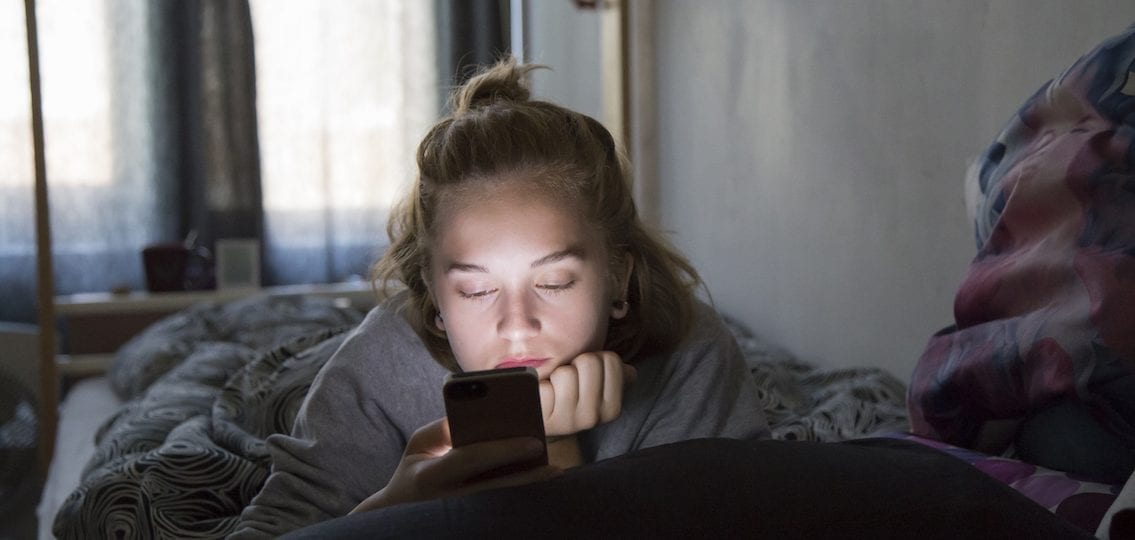Tired teen girl on smartphone