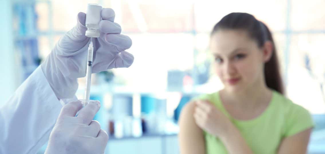 HPV vaccine being prepared for a teenage girl in the background