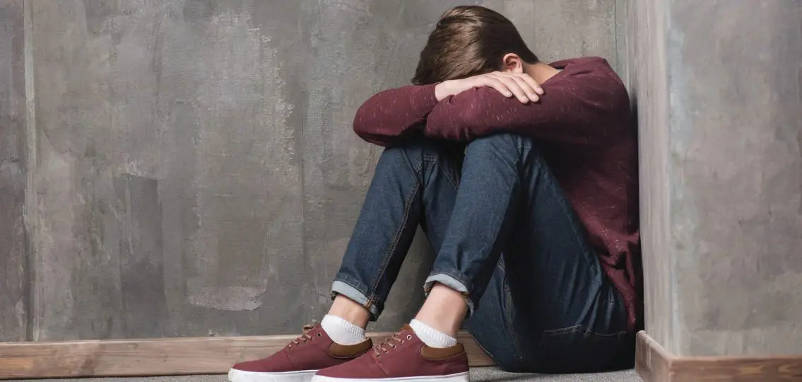 Crying teen boy in corner grieving