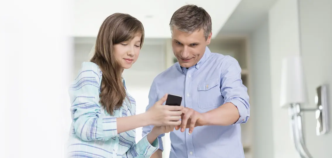 Father and daughter using smart phone at home