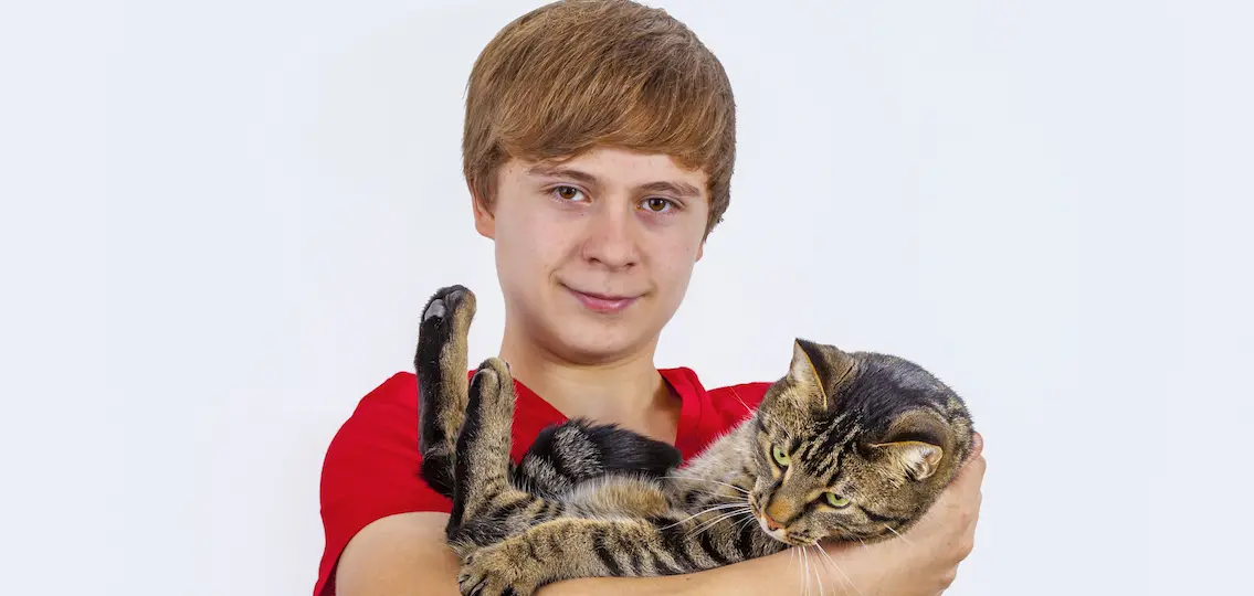 teen boy hugging with his cute tiger cat and smiling