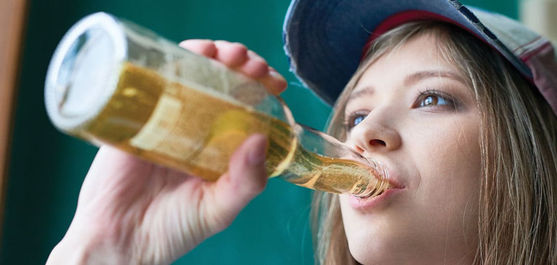 young teen Girl In Cap Drinking Beer From Bottle