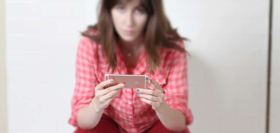 Teen girl on phone texting face blurred