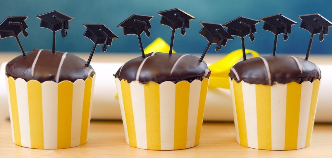 Yellow and blue theme graduation party cupcakes with cap hats toppers and decorations.