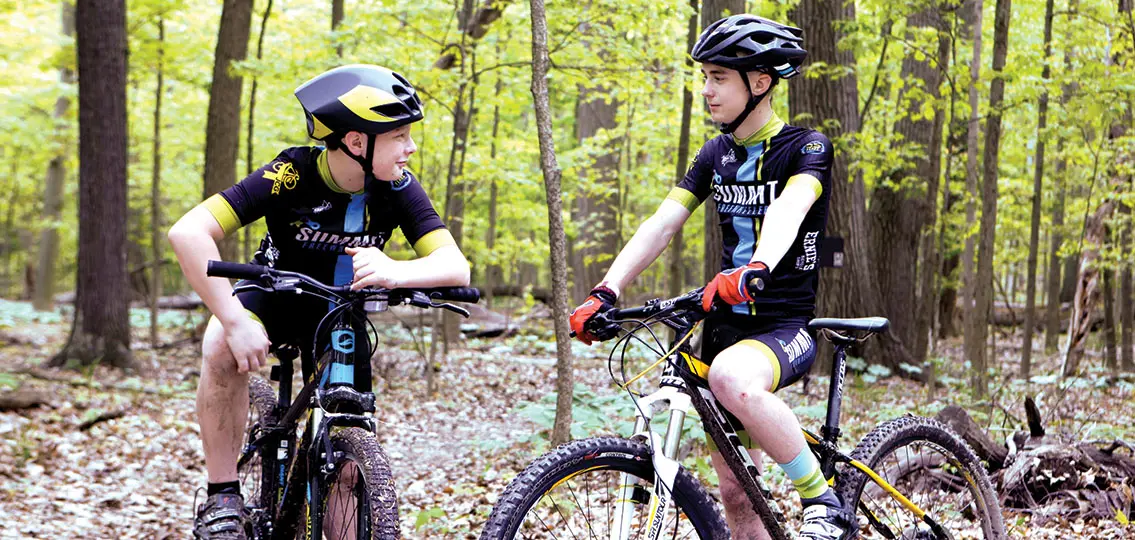 athletic teen boys on bikes in woods dressed for a race