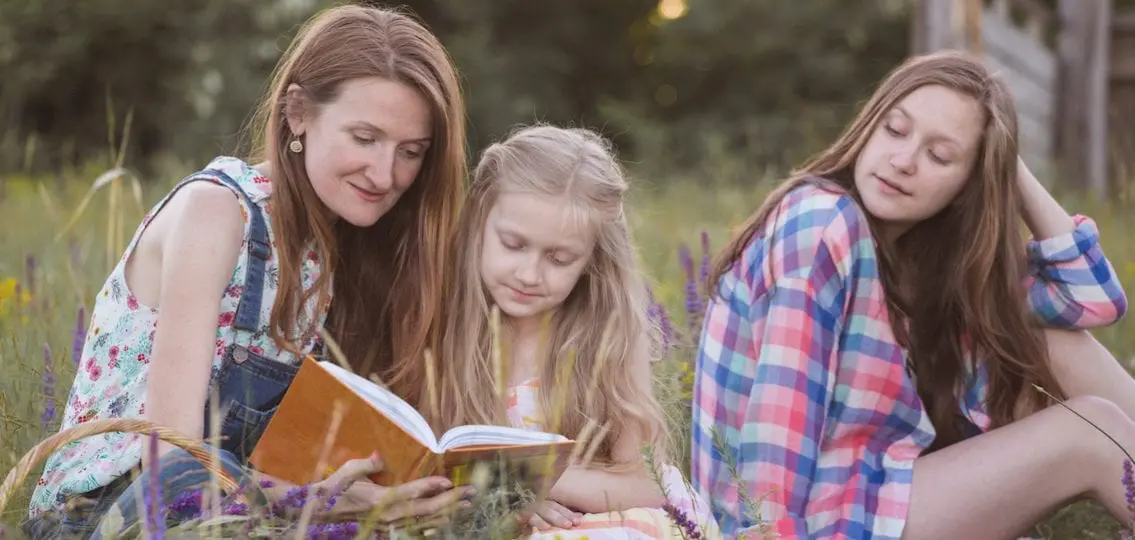 Family (mom and teen daughters) reading together outside
