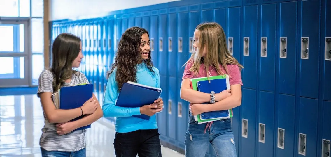 Middle school girls talking in hallway by lockers